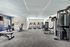 Modern fitness center with state-of-the-art equipment including treadmills, stationary bikes, and weight machines, bathed in natural light from large windows.
