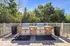 Charming outdoor patio with dual stone barbecue grills surrounded by lush greenery, perfect for social gatherings.