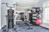 Modern gym space with state-of-the-art equipment, featuring weight racks, exercise balls, and a multi-functional workout machine against a bright windowed wall.