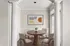 Elegant dining area with modern furniture, featuring a round wooden table and four stylish chairs, enhanced by contemporary artwork and natural lighting.