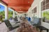 Inviting outdoor patio with stylish striped seating, wooden ceiling, and lush garden view &mdash; perfect for relaxation or entertaining.