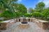 Inviting outdoor barbecue area with stone fire pit and lush greenery, perfect for entertaining and relaxation.