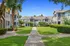 Charming apartment complex with lush green lawns, palm trees, and inviting pathways under a clear blue sky.