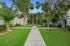 Beautifully landscaped community with lush greenery and palm trees lining a serene walkway between charming multi-unit buildings.