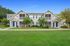 Charming two-story apartment complex with vibrant blue doors, surrounded by lush greenery and well-manicured lawns.