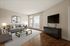 Inviting living room with sleek hardwood floors, plush gray sofa, contemporary glass coffee table, and large windows letting in abundant natural light.