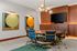 Contemporary meeting room with a round wooden table, six stylish chairs, geometric artwork, and a modern chandelier, creating a sophisticated ambiance.