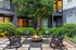 Charming outdoor patio with cozy fire pit surrounded by elegant rocking chairs and lush greenery.