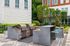 Upscale outdoor barbecue area with modern grills and vibrant turquoise seating, framed by lush greenery in a stylish apartment complex courtyard.