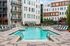 Luxurious apartment complex featuring a pristine outdoor pool surrounded by stylish lounge chairs and modern architecture.