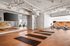Contemporary fitness room with sleek wooden flooring, equipped with yoga mats and cutting-edge exercise bikes, set against a backdrop of modern ductwork and mirrored walls.