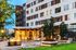 Modern apartment complex with illuminated leasing center entrance, lush landscaping, and elegant facade.