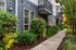 Charming apartment exterior with modern gray facade, lush landscaping, and inviting pathways.