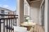 Charming balcony with cozy seating and fresh flowers overlooking a modern residential complex.