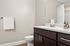 Elegant bathroom featuring a sleek dark wood vanity, modern sink, and inviting neutral tones with stylish decor elements.
