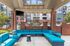 Chic outdoor seating area with vibrant blue cushions under a covered patio, surrounded by stylish brick architecture.