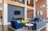 Chic and modern living room with vibrant blue and green furniture, featuring a wave-textured accent wall, sleek lighting, and stylish d&eacute;cor.
