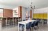 Modern open-concept dining area with sleek furniture, stylish bar seating, and vibrant brick accents.