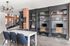 Chic apartment office space featuring modern desks, stylish shelving, and a sleek spiral staircase, illuminated by a contemporary chandelier.