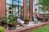 Charming outdoor patio with stylish hanging chairs and vibrant floral arrangements against a modern brick facade.