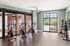 Bright fitness room featuring modern exercise bikes, large windows with serene views, and colorful free weights on sleek racks.