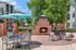 Elegant outdoor patio with a cozy brick fireplace and stylish seating under a vibrant blue umbrella, perfect for relaxing and entertaining.
