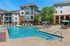 Modern apartment complex with inviting swimming pool, sun loungers, and shaded seating areas, perfect for relaxation and leisure.