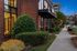 Inviting urban apartment exterior with elegant brick facade, lush greenery, and charming sidewalk view at dusk.