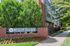 Inviting Wesley Village entrance with vibrant landscaping, highlighting urban-style brick architecture amidst lush greenery.