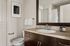 Elegant modern bathroom featuring a sleek vanity with a large mirror, stylish fixtures, and contemporary art piece.