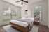 Bright and inviting bedroom with large windows, modern decor, and a cozy atmosphere.