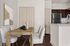 Modern apartment interior showcasing a chic dining area with elegant chairs and a stylish wooden table, complemented by an open-plan kitchen with sleek appliances.