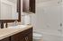 Elegant bathroom featuring a sleek granite countertop, modern sink with chrome faucet, and a luxurious bathtub with crisp white tiles.