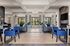 Luxurious modern living room boasting elegant blue chairs, stylish gray sofas, and a cozy fireplace with ample natural light.