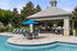 Inviting outdoor pool area with elegant sun loungers, shaded seating under a stylish pavilion, and a vibrant blue umbrella.