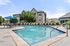 Inviting outdoor pool area with stylish lounge chairs and shaded seating, perfect for relaxation and leisure in a modern apartment community.