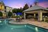 Charming apartment pool area with elegant gazebo, lush greenery, and stylish lounge chairs at sunset.