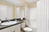 Modern bathroom with sleek fixtures, granite countertop, and a pristine bathtub, exuding elegance and comfort.