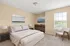 Elegant bedroom featuring a plush king-size bed, modern nightstands, contemporary artwork, and a sunlit window that fills the space with natural light.