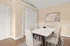 Elegant dining room with a sleek white table, beige chairs, and modern wall art, featuring natural light and a minimalist decor.