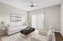 Bright and elegant living room with cozy modern furniture, large windows with blinds, and tasteful artwork on the wall.