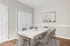 Elegant dining room with a modern white table, comfortable chairs, and chic artwork, complemented by sleek wooden flooring.