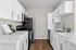 Modern kitchen with sleek white cabinetry, stainless steel appliances, and elegant countertops with wood flooring.
