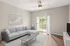 Bright and modern living room with a sleek gray sofa, elegant coffee table, and natural light streaming through sliding glass doors to a balcony.