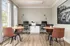 Bright and modern office space featuring stylish wood floors, elegant round tables, and leather chairs, enhanced by natural light from large windows.