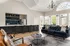 Elegant living area with a modern kitchen, stylish bar seating, plush navy sofa, and abundant natural light.