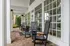Inviting porch featuring elegant black rocking chairs and large glass-paneled windows, perfect for relaxing afternoons.