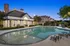 Inviting evening view of a luxurious apartment complex with a sparkling swimming pool surrounded by lush greenery and elegant architecture.