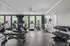 Bright and modern fitness center featuring cardio machines and free weights, illuminated by large windows.