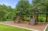 Charming outdoor playground with climbing walls, swings, and slides set against a lush green backdrop, perfect for family enjoyment.